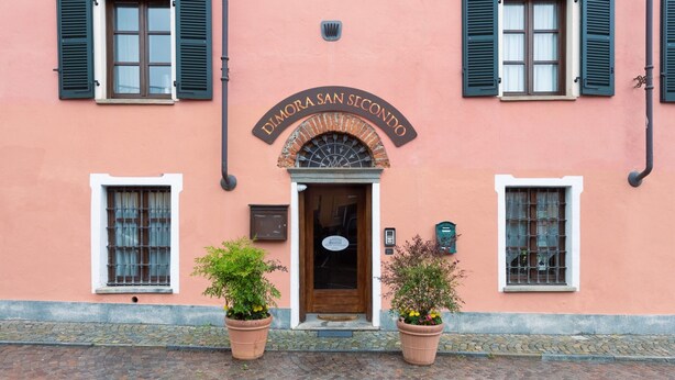 A building with a sign reading "Dimora San Secondo" above the entrance. There are two potted plants in front of the entrance. - Dimora San Secondo (San Secondo di Pinerolo)