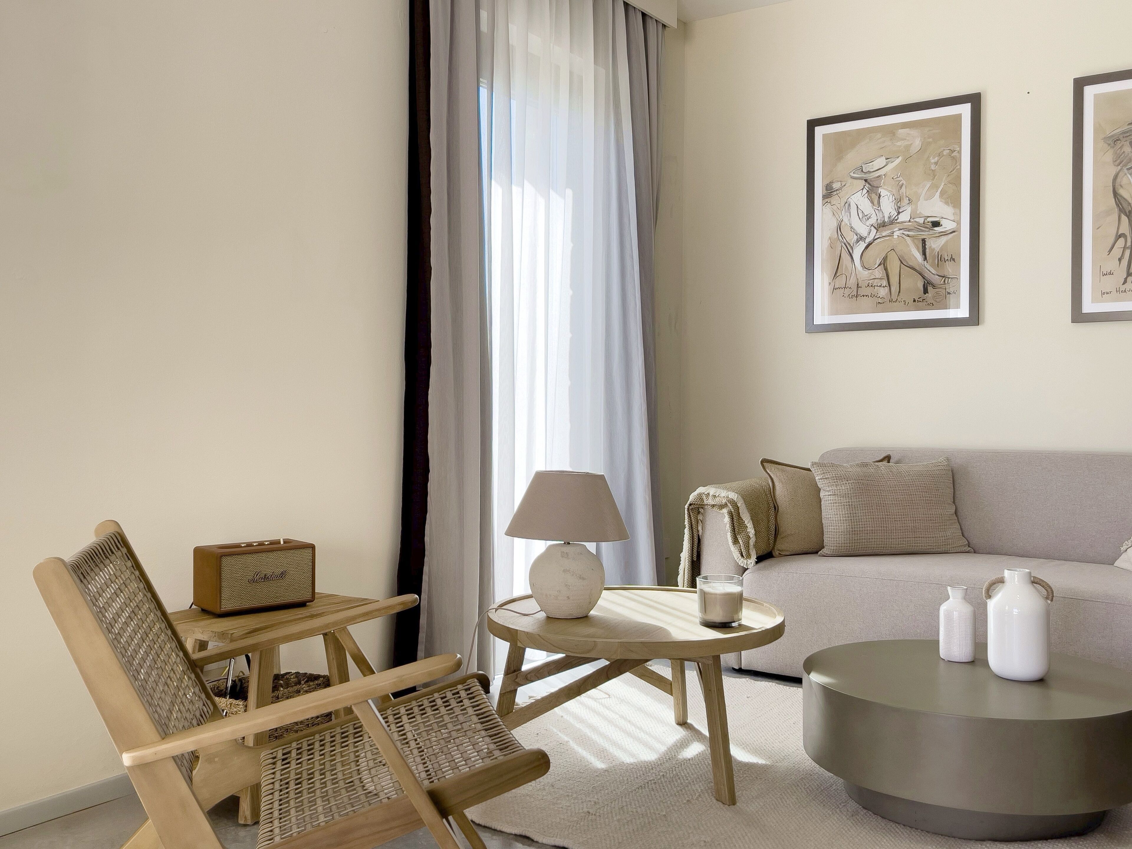 Un salon comprenant un canapé, deux fauteuils, une table basse, une lampe et deux œuvres d’art encadrées.