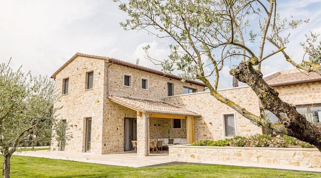 Un bâtiment en pierre doté d’un patio couvert et d’une pelouse.