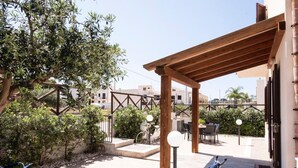 An outdoor patio area with a wooden pergola, seating, and a bicycle. - Casa Orchidea Bianca with large equipped veranda (San Vito Lo Capo)