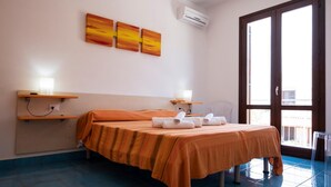 Ein Hotelzimmer mit einem Bett, zwei Nachttischen, einem Fenster und einer Klimaanlage.