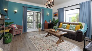 Un salon comprenant un canapé, une table basse, un tapis et une grande fenêtre avec des rideaux.