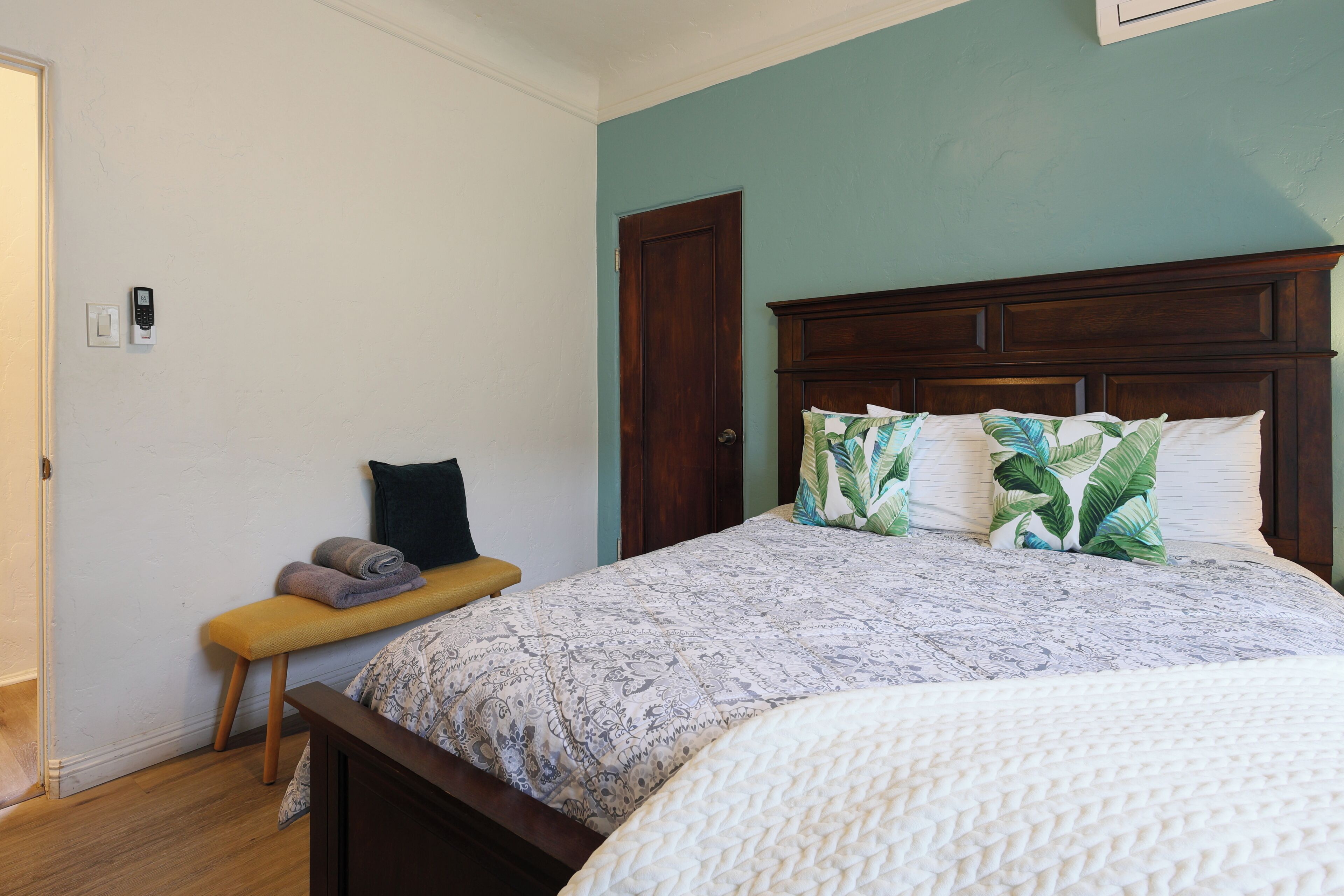 Een slaapkamer met een houten bed, een bankje en een deur.