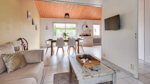 Een moderne woonkamer met een bank, salontafel en een eethoek met stoelen en een tafel.