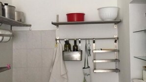 Una cucina con scaffali in acciaio inossidabile, un appendiabiti e un asciugamano bianco.