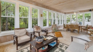 A spacious living room with large windows, wooden ceiling, and a cozy seating area.