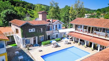 Relax by the large pool surrounded by a patio area with outdoor seating and take in the scenic views of the lush hillside landscape.