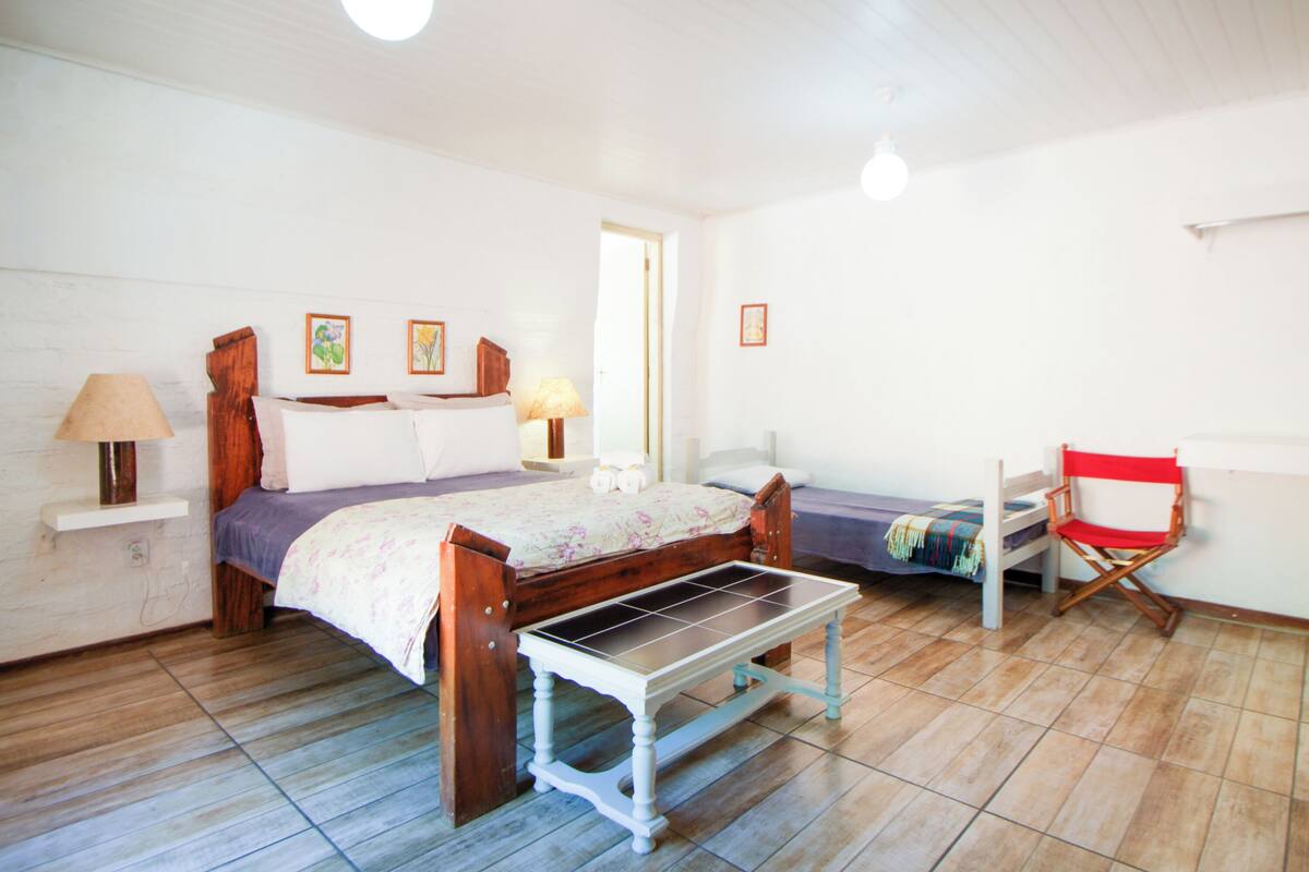 A bedroom with a wooden bed, a small table, a chair, and a bench.