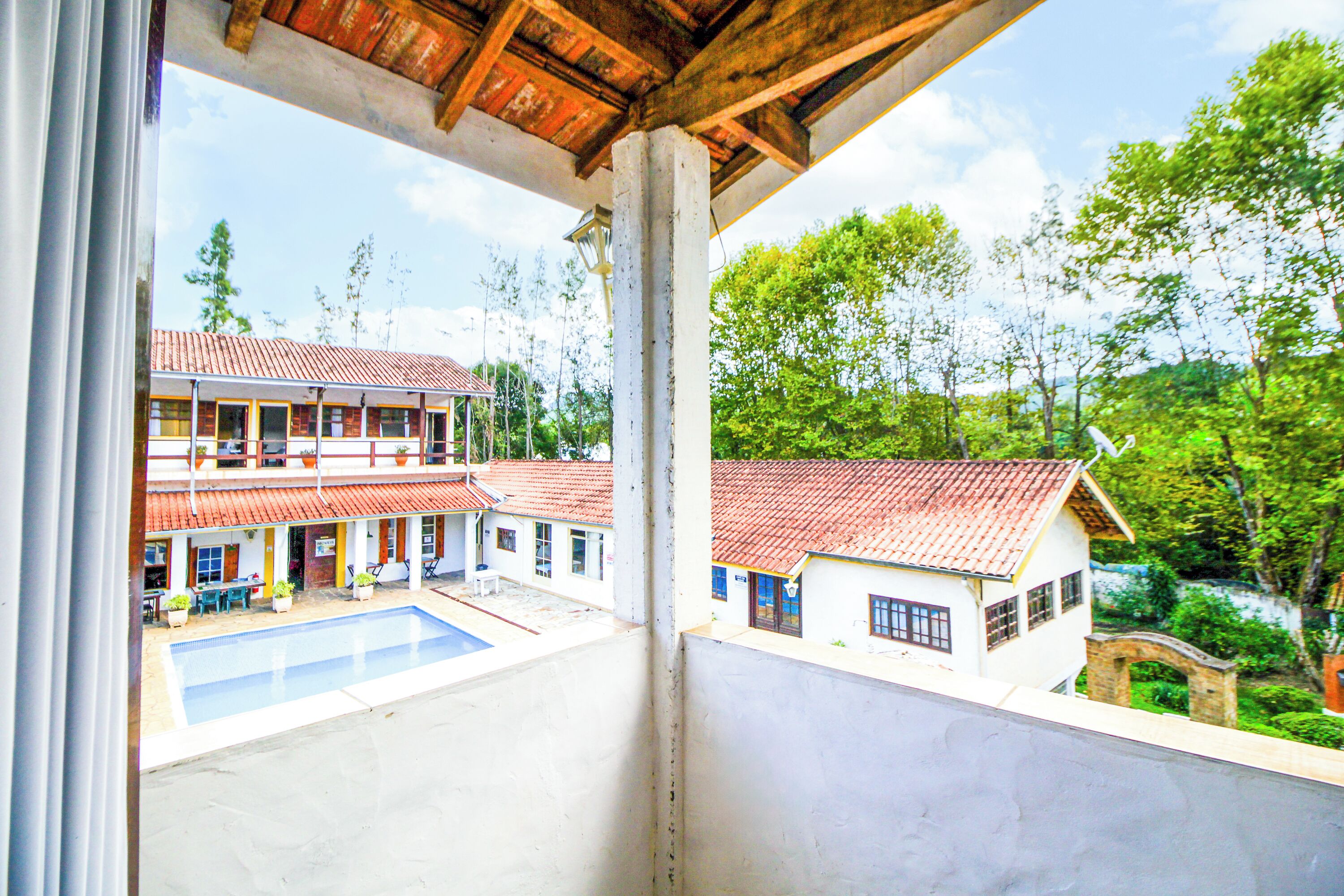 A view of a building with a swimming pool, multiple balconies, and a red-tiled roof.