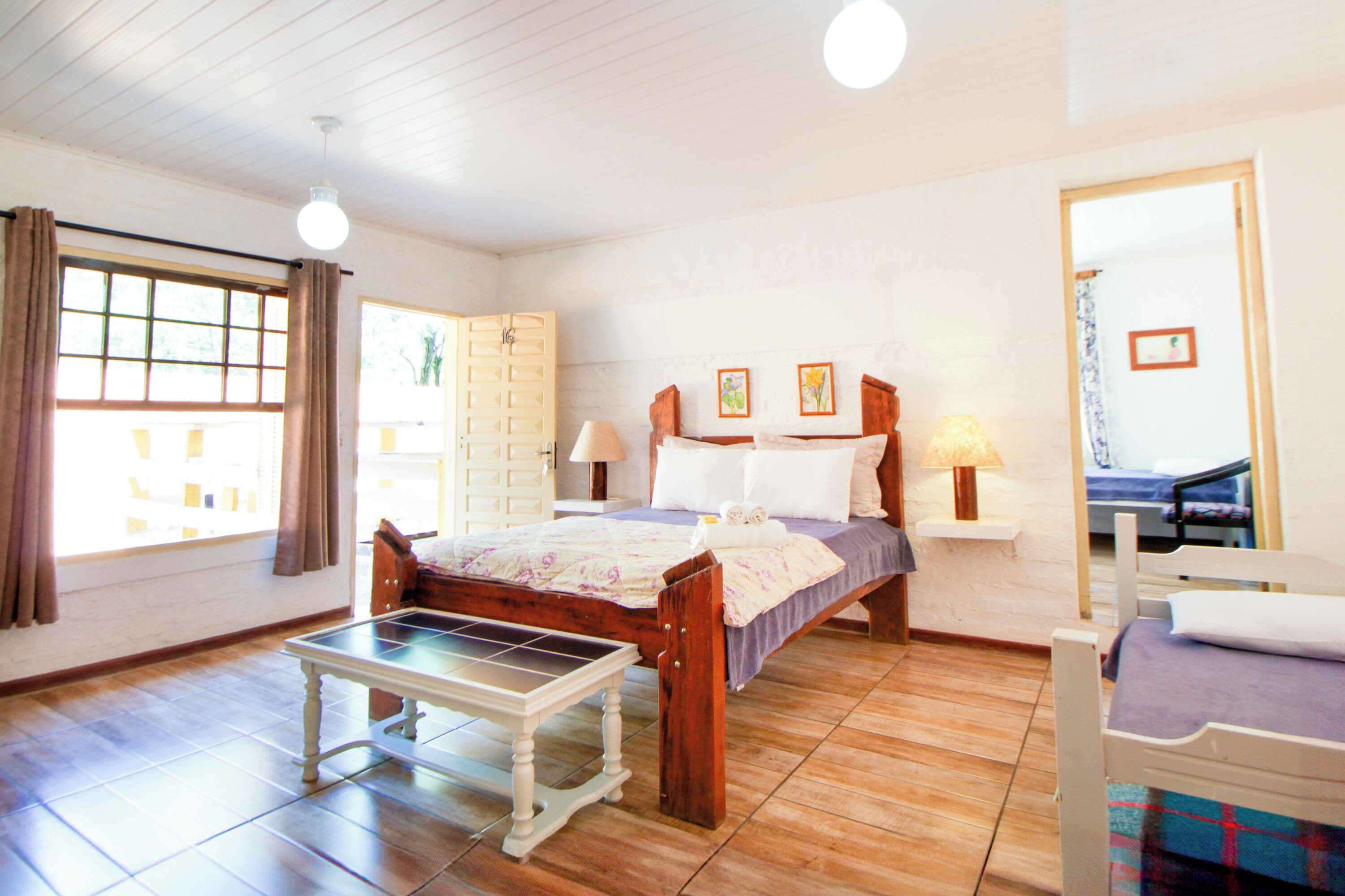 A bedroom with a bed, bedside tables, a bench, and a window with curtains.