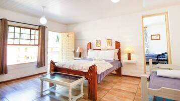 A bedroom with a bed, bedside tables, a bench, and a window with curtains.