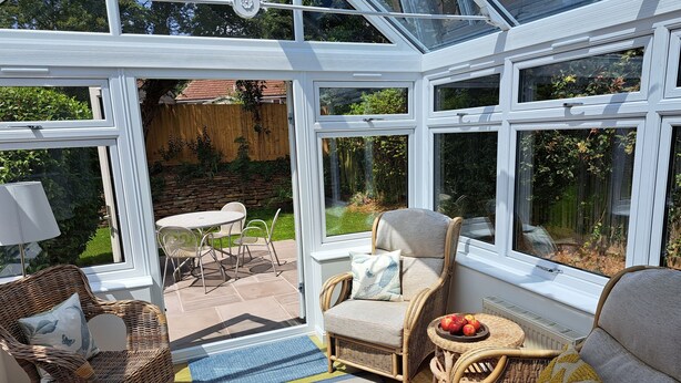 A conservatory with wicker furniture, a table, and chairs.