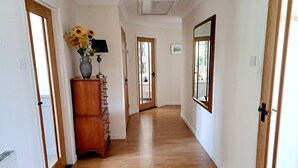 A hallway with wooden floors, white walls, and a wooden cabinet with a vase of flowers.