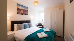 Een hotelkamer met een bed, een stoel, een kledingkast en een schilderij aan de muur.