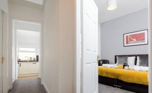Habitación de hotel con cama, mesita de noche, ventana y puerta que da a un baño.