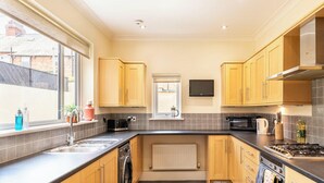 Une cuisine moderne avec des meubles en bois, un four encastré, un four à micro-ondes et une grande fenêtre qui laisse entrer la lumière naturelle.