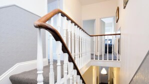 Eine Treppe mit weißen Balustern und einem hölzernen Geländer, die zu einer oberen Etage führt.
