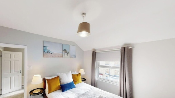 Une chambre à coucher avec un lit, des lampes de chevet, une fenêtre avec des rideaux et un luminaire au plafond.