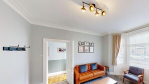 Un salon avec un canapé, un fauteuil et un luminaire suspendu au plafond.
