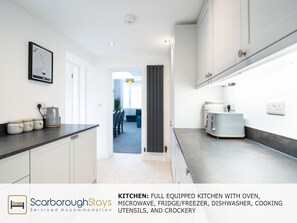 Fully equipped kitchen with oven, microwave, fridge, and dishwasher, plus cooking utensils and crockery.