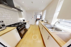 A modern kitchen with white cabinets, a wooden countertop, a stainless steel sink, and a gas stove.