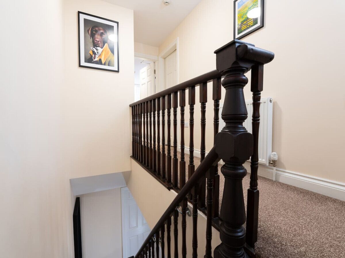 A staircase with a black balustrade, beige walls, and a framed picture on the wall.