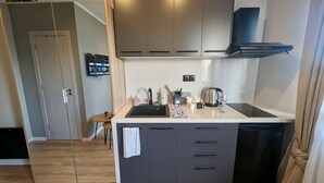 A modern kitchen with grey cabinets, a black dishwasher, a coffee maker, and a small dining table. - Lily's Studio 4 by Bulgarentals - Central Sofia (Sofia)