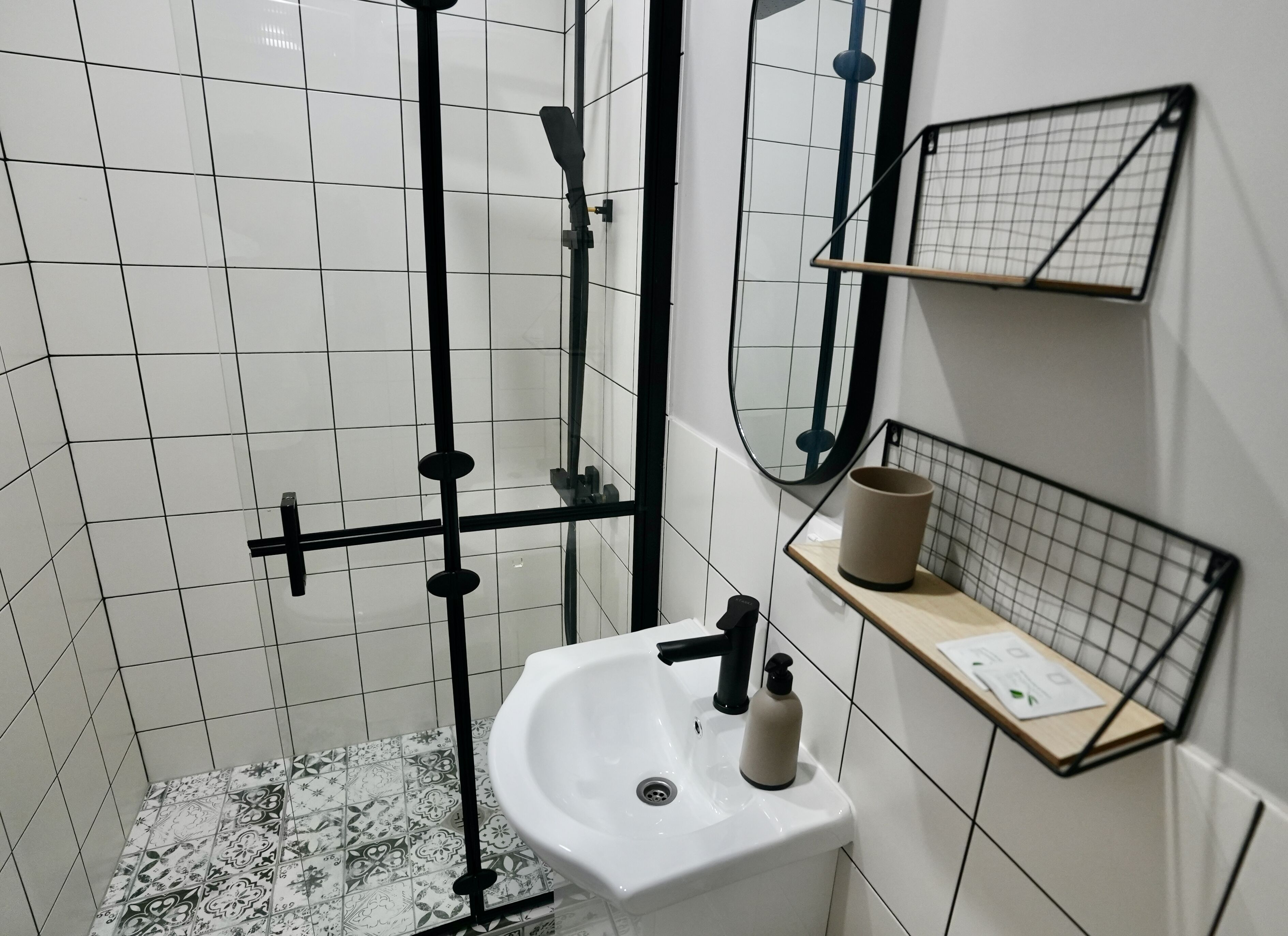 Een badkamer met een witte wastafel, een spiegel, een handdoekhouder en een douchehoek.