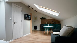 A modern living room with a dark sofa, a small round table, and a ceiling skylight.