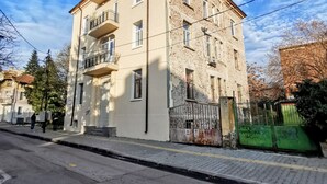 A multi-story building with a beige facade, balconies, and a green gate.