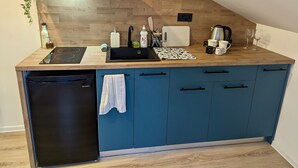 A compact kitchen with a black dishwasher, a built-in stove, a sink, and blue cabinets.