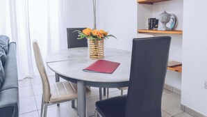 Ein Essbereich mit einem runden Tisch, zwei Stühlen, einer Blumenvase und einer roten Ordner.
