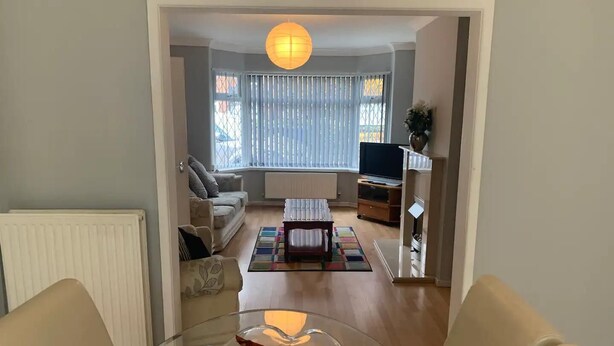 Un salon avec une table en verre, deux canapés, un téléviseur et un radiateur.