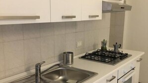 Een kleine keuken met een roestvrijstalen spoelbak, een gasfornuis en een inbouwoven.