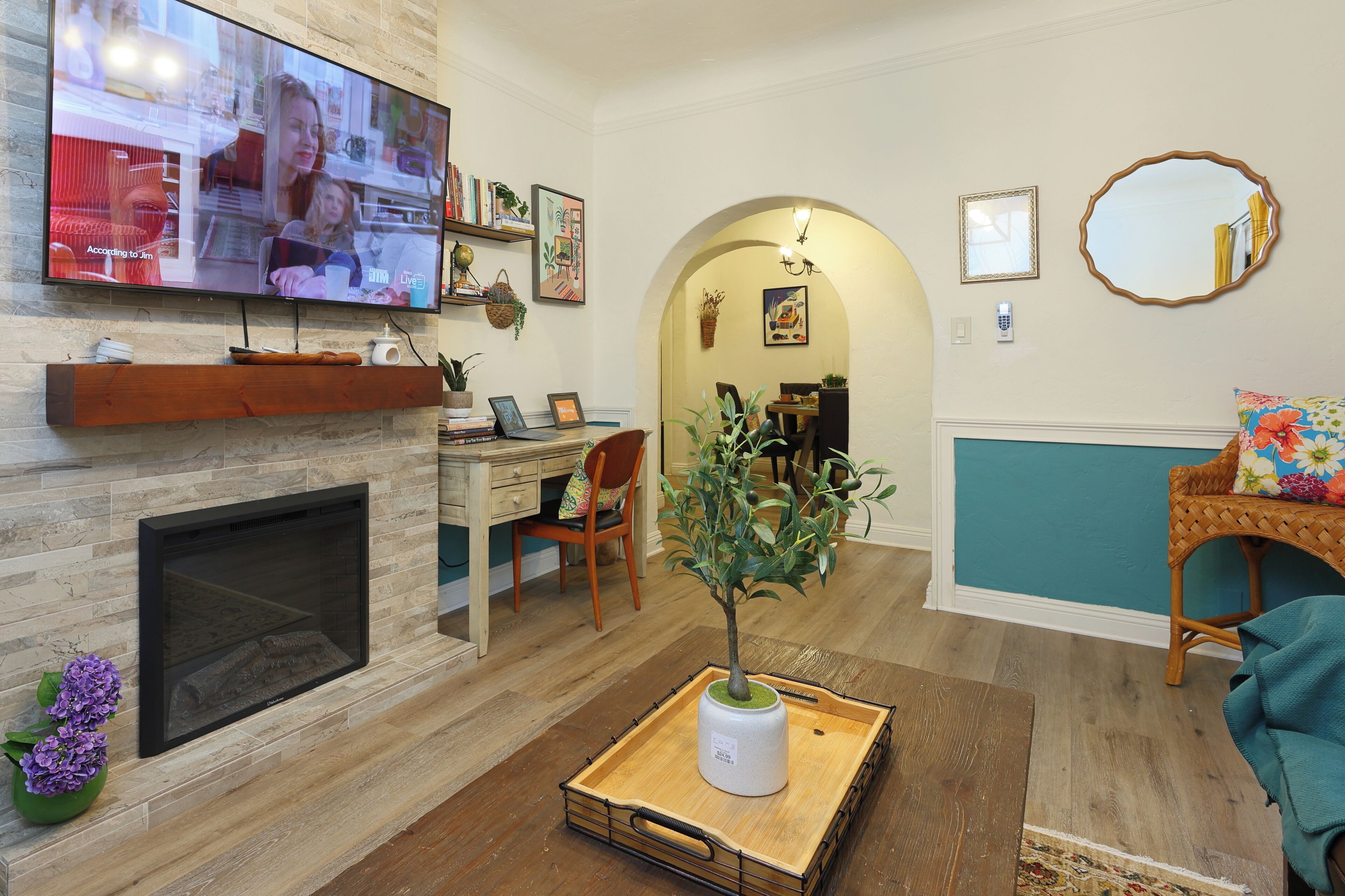 Een woonkamer met een open haard, televisie en een eethoek met een tafel en stoelen.