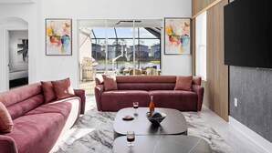 A modern living room with two red sofas, a coffee table, and abstract paintings on the walls.