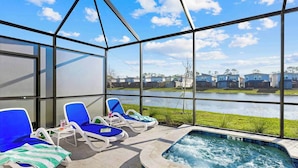 A glass-enclosed outdoor area with lounge chairs and a hot tub.