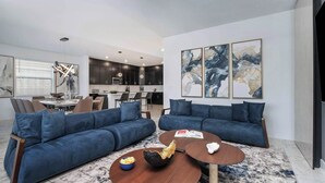A modern living room with two blue sofas, a wooden coffee table, and abstract art on the wall. - The Magical | Unbelievable wizard theme BR & more magical RMs, near Harry P Land (Orlando)