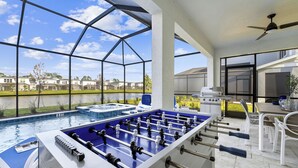 A pool table and foosball table in a spacious indoor area with large windows overlooking a residential neighborhood. - The Magical | Unbelievable wizard theme BR & more magical RMs, near Harry P Land (Orlando)
