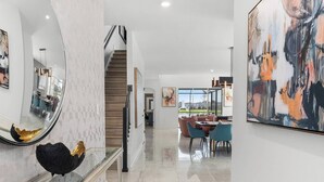 Un intérieur moderne avec un escalier, un coin repas et des œuvres d’art.