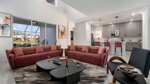 A modern living room with a sectional sofa, a coffee table, and a view of the kitchen.