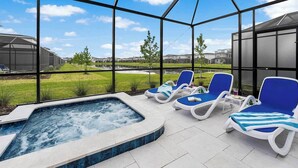 A spa area with a hot tub, lounge chairs, and a view of a residential neighborhood.