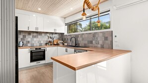 Een moderne keuken met witte kastjes, een houten aanrechtblad en een groot raam dat voor natuurlijk licht zorgt.