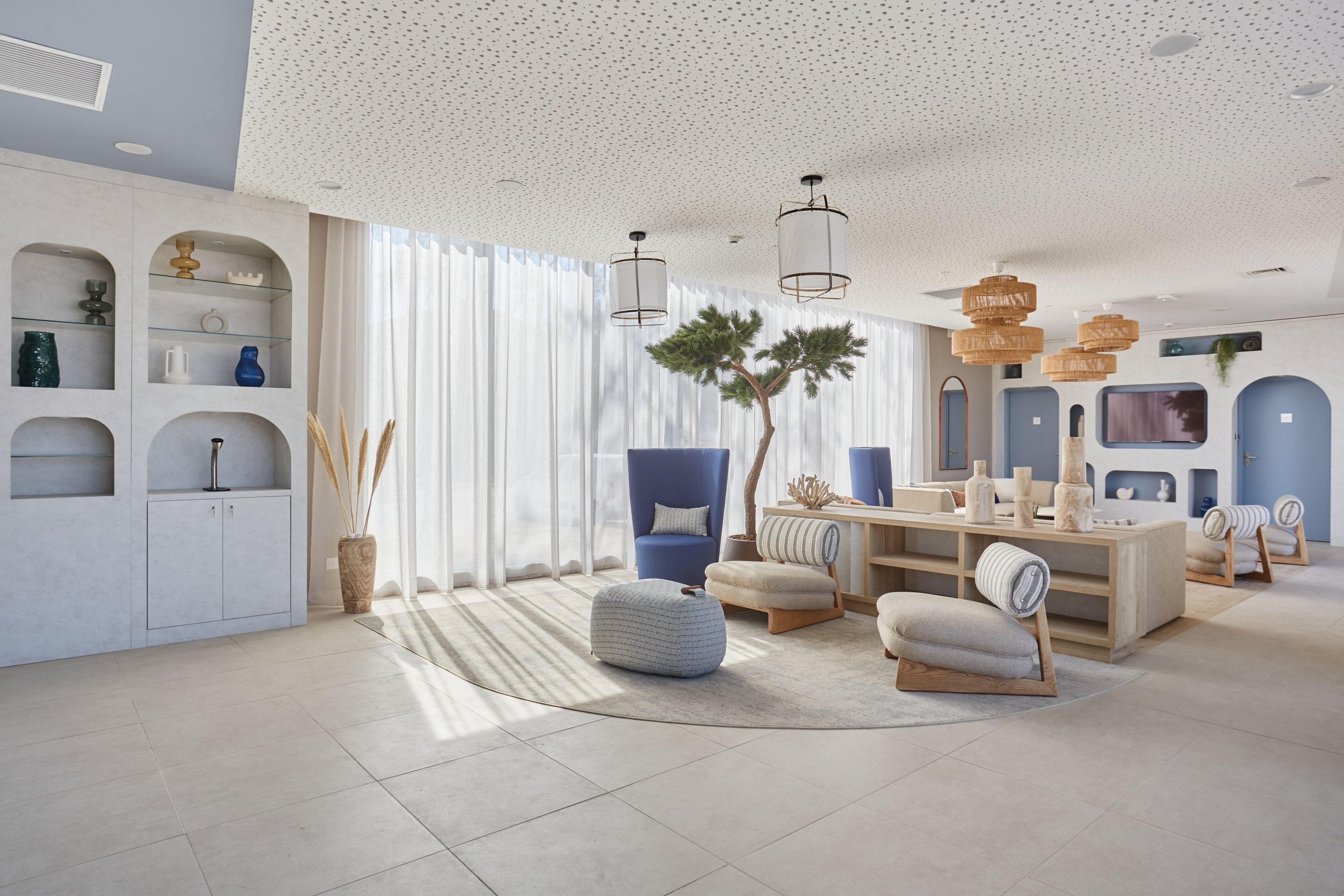 A modern living room with a large window, a blue armchair, a wooden coffee table, and a white sofa.