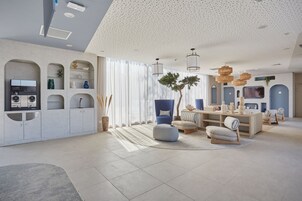 Una sala de estar moderna con área de cocina, que cuenta con armarios empotrados, una mesa de comedor y un ventanal con cortinas ligeras.