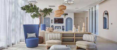 Una sala moderna con un sillón azul, un reposapiés redondo y una mesa de centro de madera.