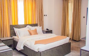 Una habitación de hotel con una cama grande, una mesita de noche y cortinas.
