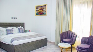 Une chambre à coucher avec un lit, une petite table, deux chaises et un tableau accroché au mur.