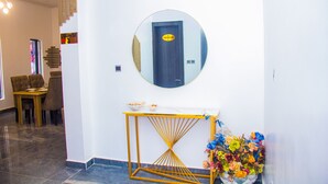Un couloir agrémenté d’un miroir rond, d’une console et d’un arrangement floral.
