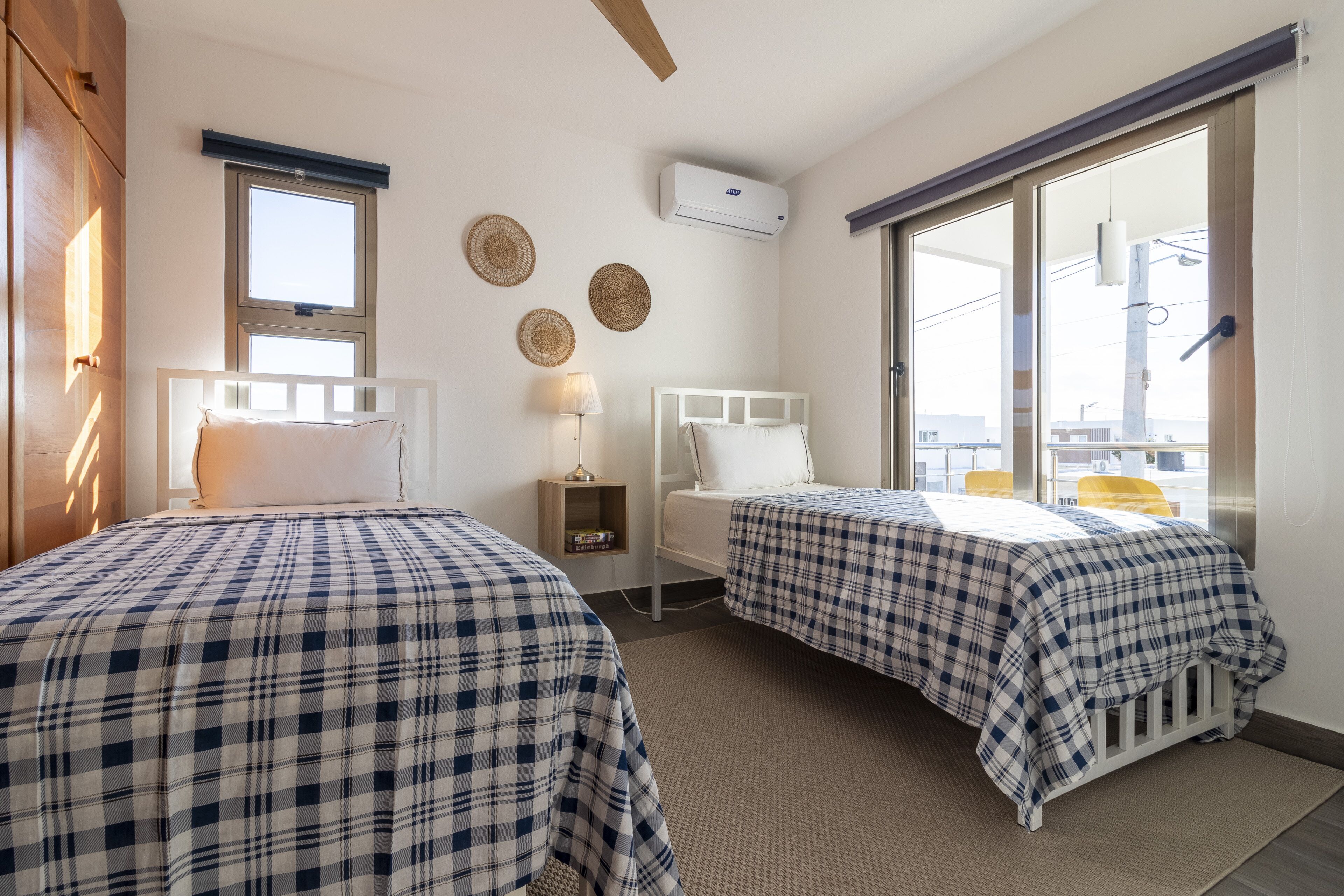 Una habitación con dos camas, ventana, aire acondicionado y vistas al exterior.